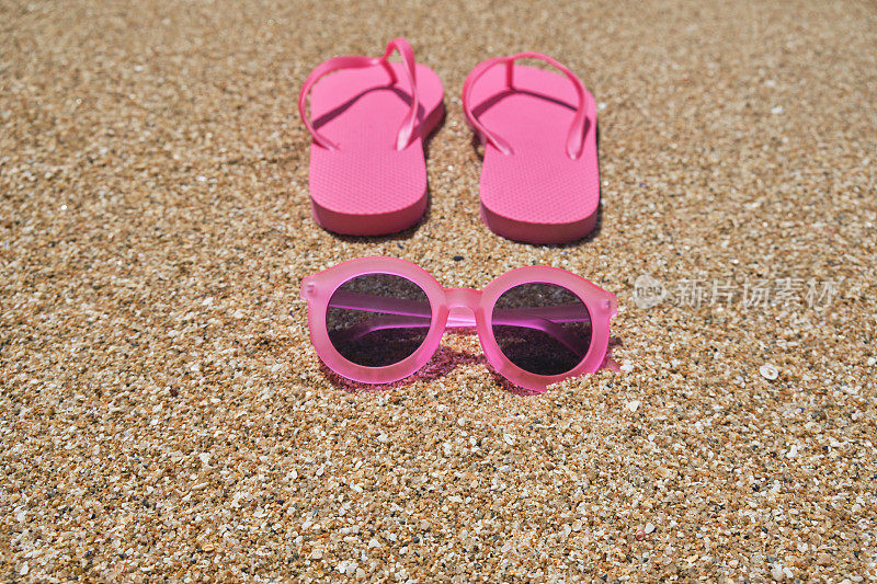 海滩假日背景，粉色太阳镜和人字拖在Pedn Vounder海滩的沙滩上，康沃尔在一个阳光明媚的六月。